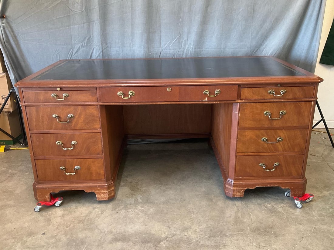Chippendale Style Desk: Late twentieth century Georgian Chippendale style mahogany office/library desk with gilt tooled leather top insert and brass bail handles. Nine total drawers with two pull out writing shelves. Some fi