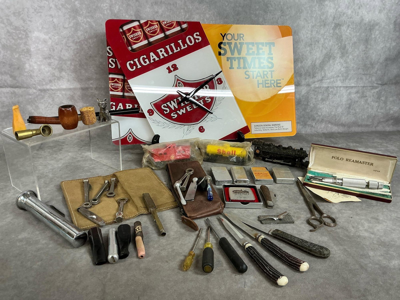Pipe Smoker's Supplies, Clock, & More: Over forty smoker's supplies, knives, lighters and more from mid to late 1900's. Swisher Sweets wall clock, crack at right top corner. Three Shell Oil train cars, Polo Reamaster pipe cleaner in box,