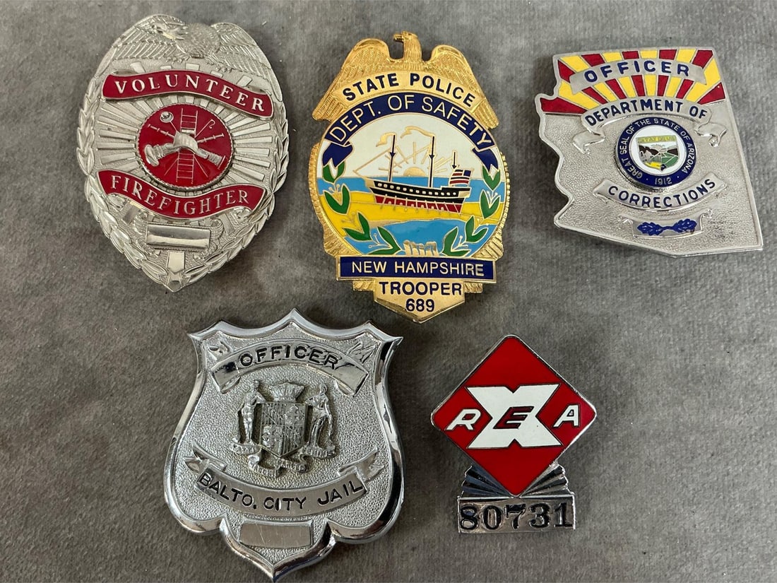 Collectible Badges: Five vintage badges. Volunteer Firefighter, New Hampshire State Police, Arizona Dept of Corrections, Baltimore City Jail, and REA. In good condition. NH Police badge measures 2 inches wide x 3 inches
