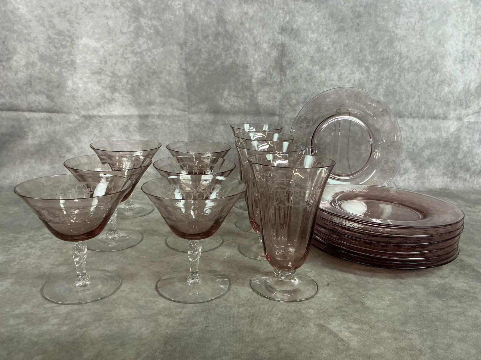 Fostoria Orchid Glass: Eighteen mid 1900's glassware. Spartan pattern by Fostoria includes eight snack plates, four tumbers, and six champagne glasses in light purple "Orchid". Tumbers have rough, chipped rims, otherwise