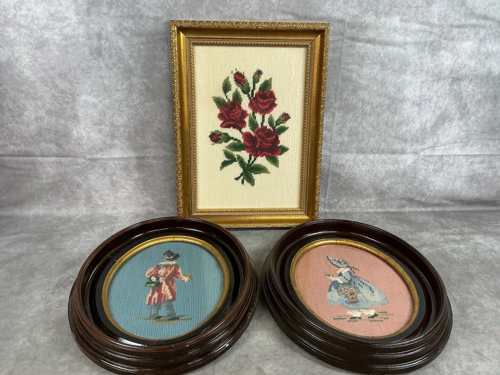 Needlepoint Pictures: Three mid to late 1900's wool needlepoint framed pictures. Roses in ornate gold frame and Victorian style boy and girl in oval wood frames. A few nicks in the wooden frames, otherwise in good