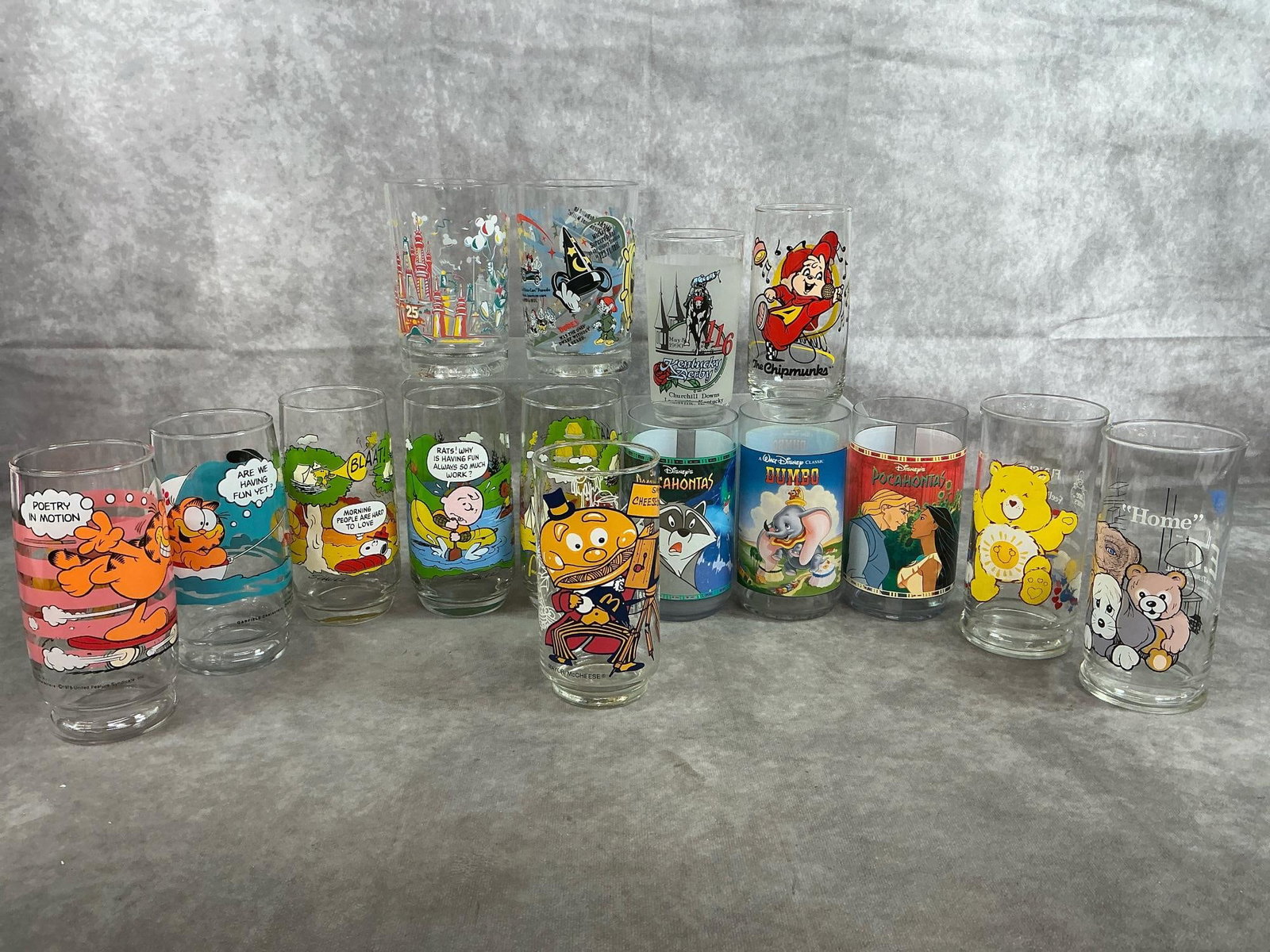 Collectible Tumblers: Fifteen 1960's - early 2000's glasses or tumblers. Includes Disney, Garfield, Peanuts, Kentucky Derby, and more. Three Disney movie tumblers are plastic, others are glass. In good condition. Average