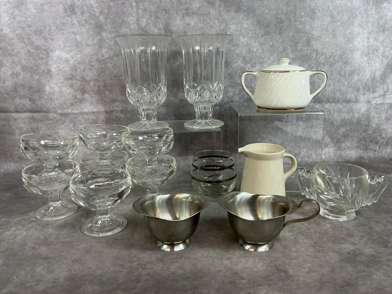 Crystal Candle Holders, Federal Glass Dessert Dishes, & More: Fifteen mid to late 1900's glass and stainless pieces. DePlomb lead crystal hurricane candle holders, seven Federal Glass footed dessert dishes, Sweet'N Low sugar bowl and Royal Doephin stainless crea