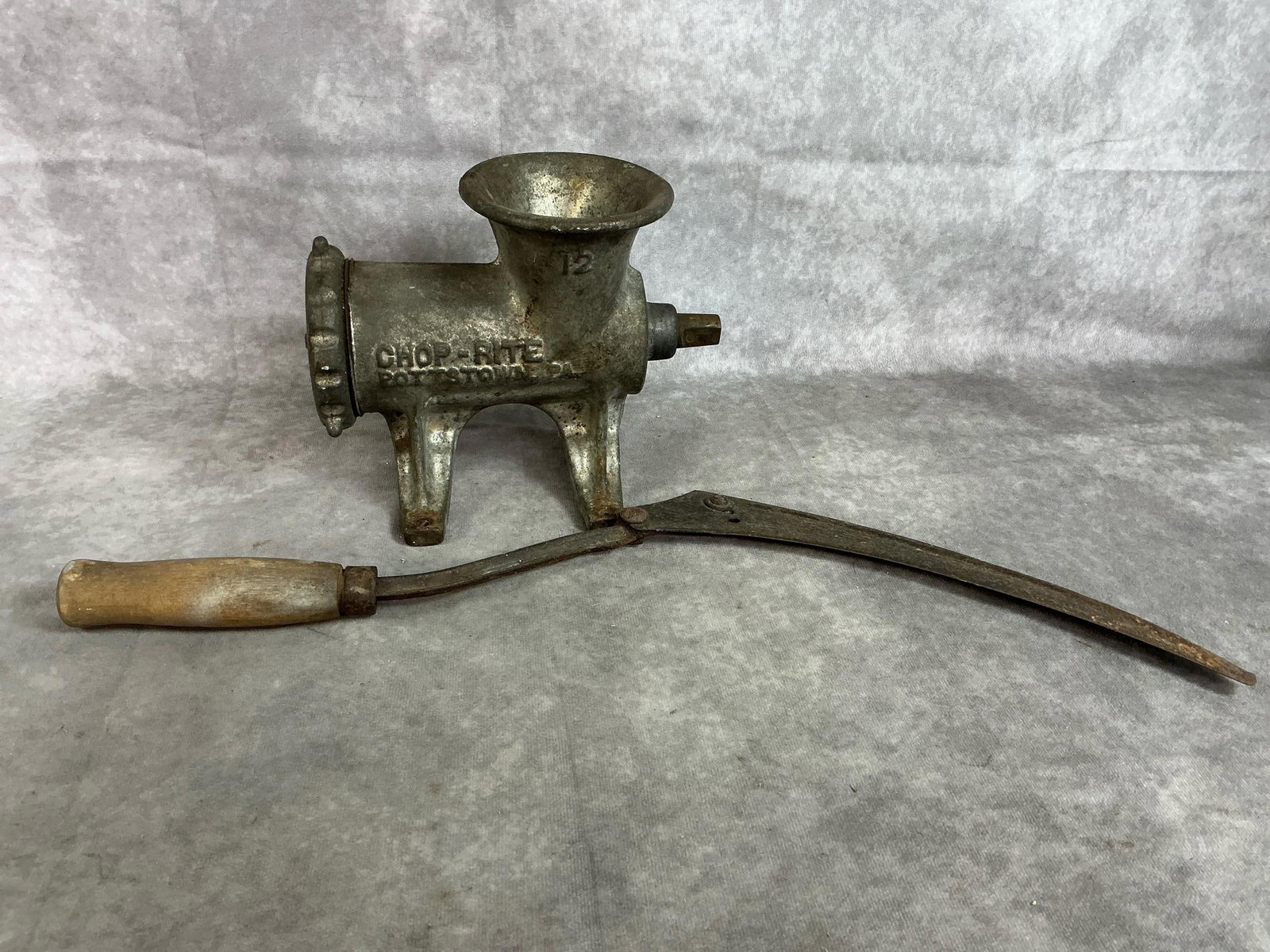 Antique Meat Grinder & Hand Sickle: Two early to mid 1900's metal tools. Chop-Rite cast iron with tin overlay meat grinder #12 and wooden handle sickle or scythe. Both have rust. Sickle measures 20 inches long x 2 inches wide.
