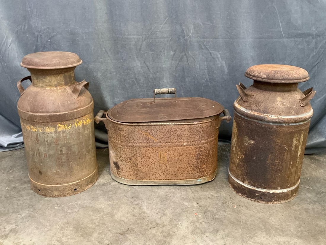 Milk Cans: Early 20th century lot of three. One tin boiler washtub, rusted with dents and holes. Two metal milk cans with rust. Boiler measures 26 inches wide x 12.5 x 18 inches tall.