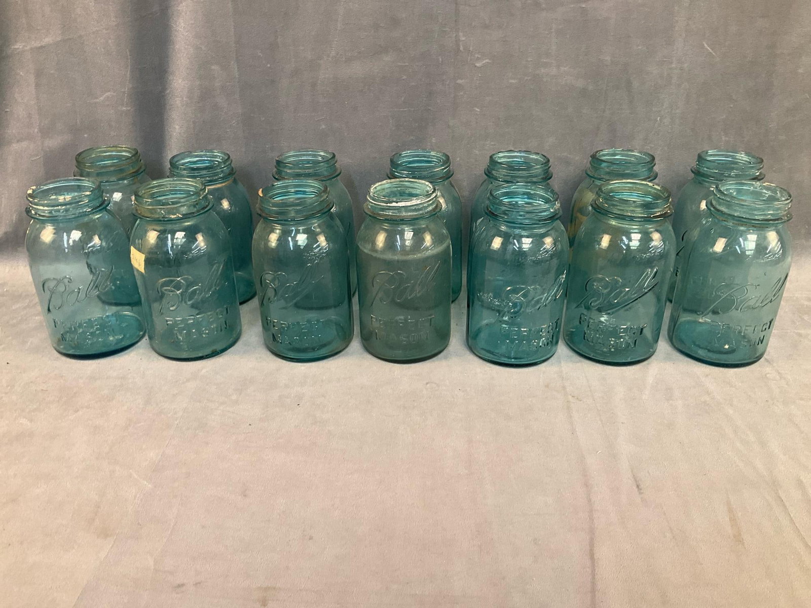 Mason Jars: Lot of fourteen early-mid 20th century "Ball Perfect Mason Jars”. One with chip, most with flea bite chips, otherwise good used condition. Measures 4 inches in diameter x 6.75 inches tall.