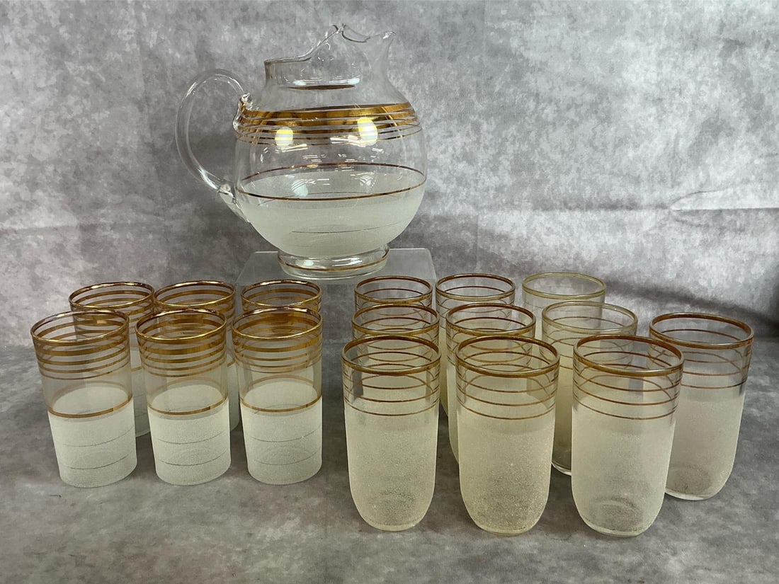 MCM Retro Pitcher & Glasses: Mid century modern glass pitcher and glasses with gold accents and frosted finish. Includes six cylinder shaped cocktail glasses and 10 cocktail glasses with rounded bottom. In good condition.