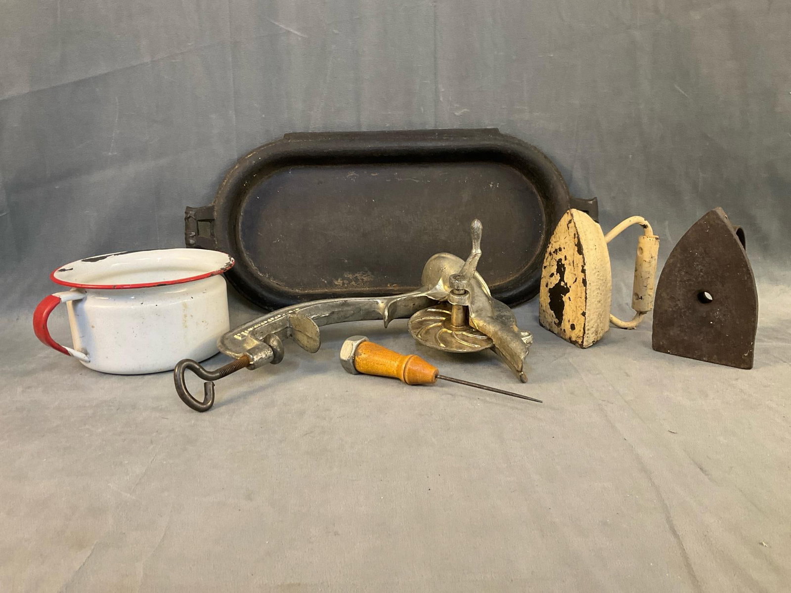 Vintage Kitchenalia: Lot of six early 20th century kitchen items. Including; ice pick, two cast iron sad irons, cast iron rectangular griddle with chipped handle, Enterprise 16 Cherry Stoner, and white and red enameled