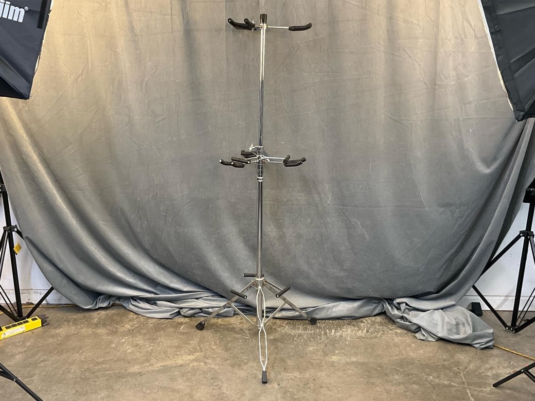 Multi Guitar Stand: Early 2000's Multi Guitar Stand with "Mirage” label. Several areas of rust, otherwise good condition. Measures 17 inches wide x 42 inches tall.