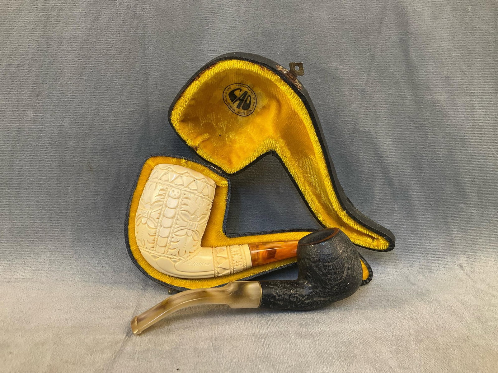 Vintage Pipes: Lot of two early 20th century pipes. One Cao Meerschaum pipe (signed "T. Bekler”) with leather case, and one Gatlin-Burlier marked pipe. Good used condition. Case measures 7 inches wide x 3.25