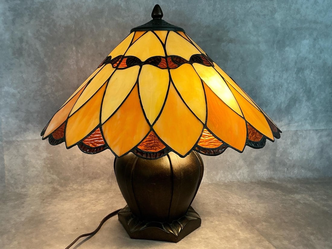 Tiffany Style Table Lamp: Stained glass Amber Tiffany Austin Mission style lamp. Resin base with two bulbs and flared pieced slag glass shade. In good condition. Measures 17.5 inches in diameter x 18 inches tall.