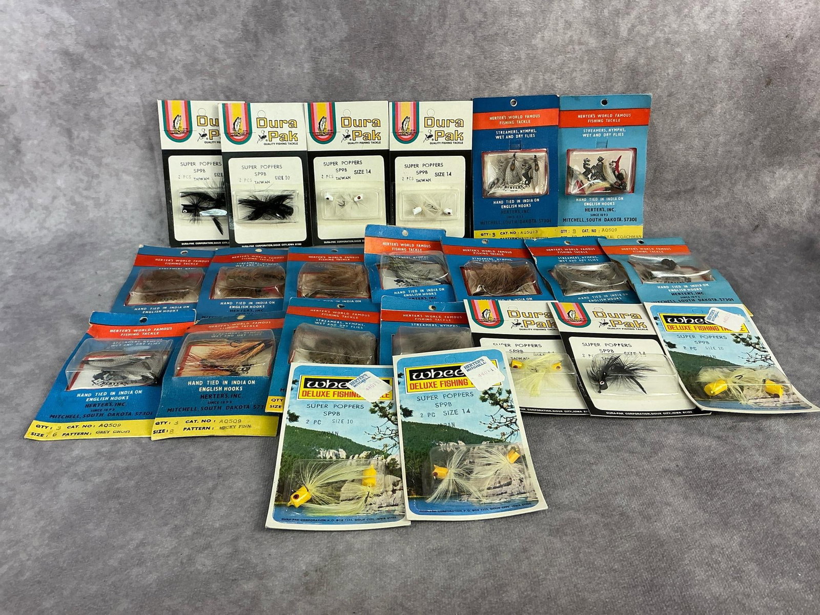 Fly Fishing Lures: Twenty two 1970s fly fishing lures made by Dura Pak in Japan and Taiwan, and by Herter's. All in original packaging, wear to packaging. Each pack measures 2.75 inches wide x 4.75 inches tall.