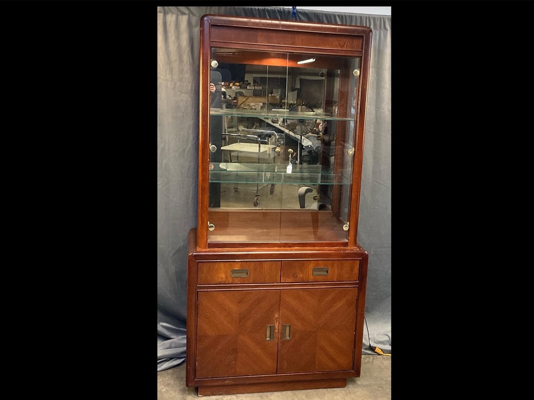 Bassett Curio Cabinet: Vintage circa 1970's Bassett Furniture curio cabinet with two drawers over two doors and two removable glass shelves, interior mirror and interior light. Light tested and works. Wear to finish,