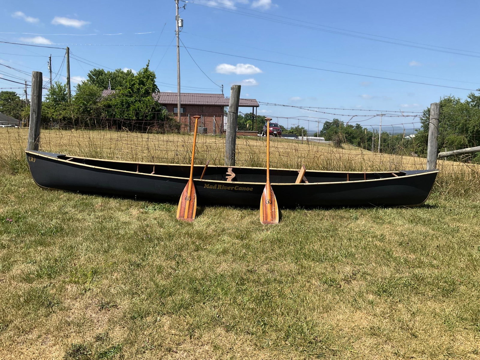 Mad River Canoe: Early 2000's Mad River Canoe with two Mad River paddles and two removable cane seats. Wear to gunwale/gunnel, scratches and missing one hatch lid. Wear commensurate with age and use, overall good