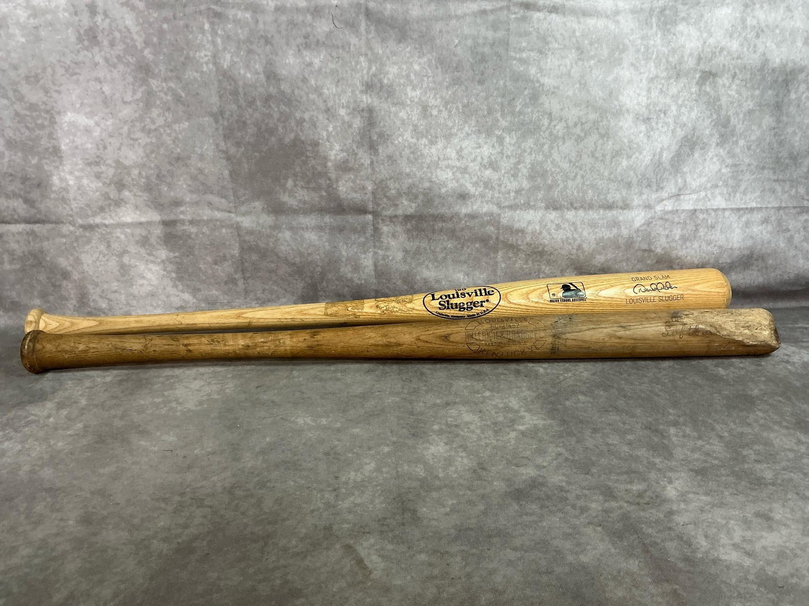 Vintage Baseball Bats: Two mid-late 1900's baseball bats. Vintage Louisville bat stamped with Hillerich and Bradsby Co. Bat has damage on end. Includes 180 Louisville Slugger "Grand Slam" bat, measures 33.5 inches in
