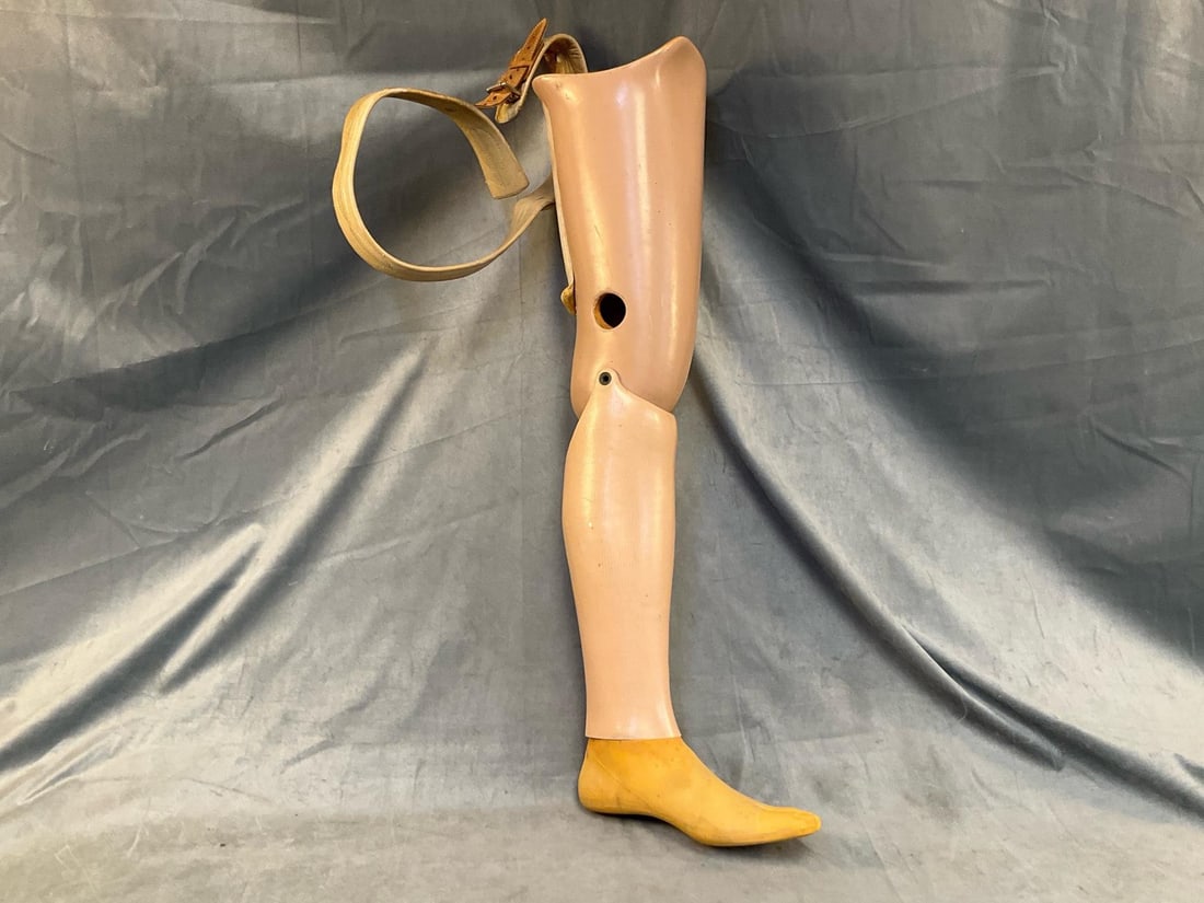 Vintage Prosthetic Leg: Mid-20th century wooden prosthetic left leg with rubber foot and leather belt. Foot marked ""Kingsley MFG. Co. / Dec 23 1985", probably later replacement. Signs of wear commensurate with age and use,