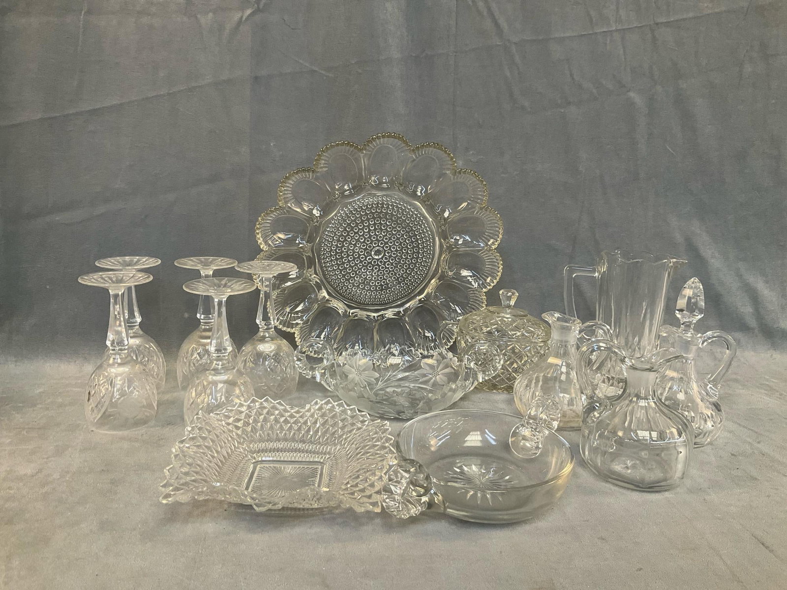 Assorted Crystal Glass: Mid-20th century lot of fourteen crystal pieces. Four wine glasses, three cruets, one pitcher, three relish dishes, one sugar and one deviled egg platter. Good condition. Egg platter measures 11.5