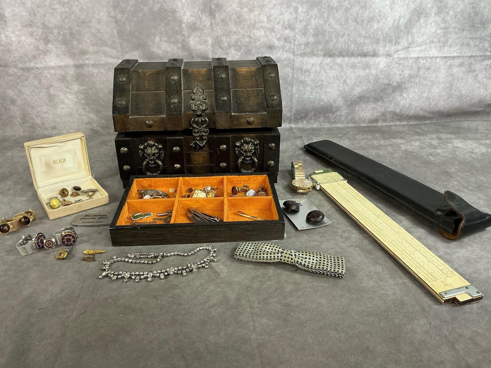 Men's Jewelry, Chest, & Slide Rule: Lot of mid 1900's men's jewelry and items. Includes Keuffel & Esser slide rule, bow tie, cuff links, tie tacks, watch, buttons, and more. Jewelry case measures 9.5 inches wide x 7.5 x 7 inches tall.