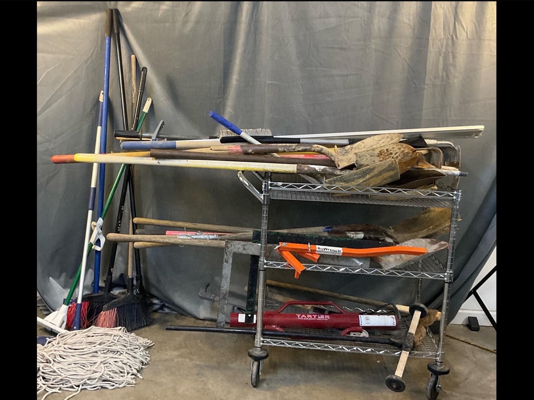 Assorted Hand Tools: Approximately 35 hand tools. Shovels, brooms, mop head, rakes, BoWrench, post driver, two squares, mattocks, sledgehammer, hoes, crowbar, Mr. Longarm, mortar hoes, and more. Cart not included. Used co