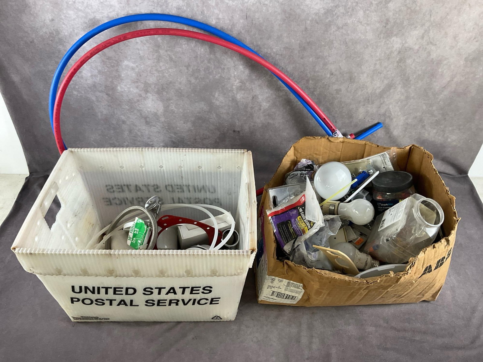 Electrical & Pluming Items: Assorted electrical and plumbing items including, light bulbs, switches, cover plates, wire nuts. Plumbing items including flexible tubing, PVC items and faucet. New and used, untested. Largest box