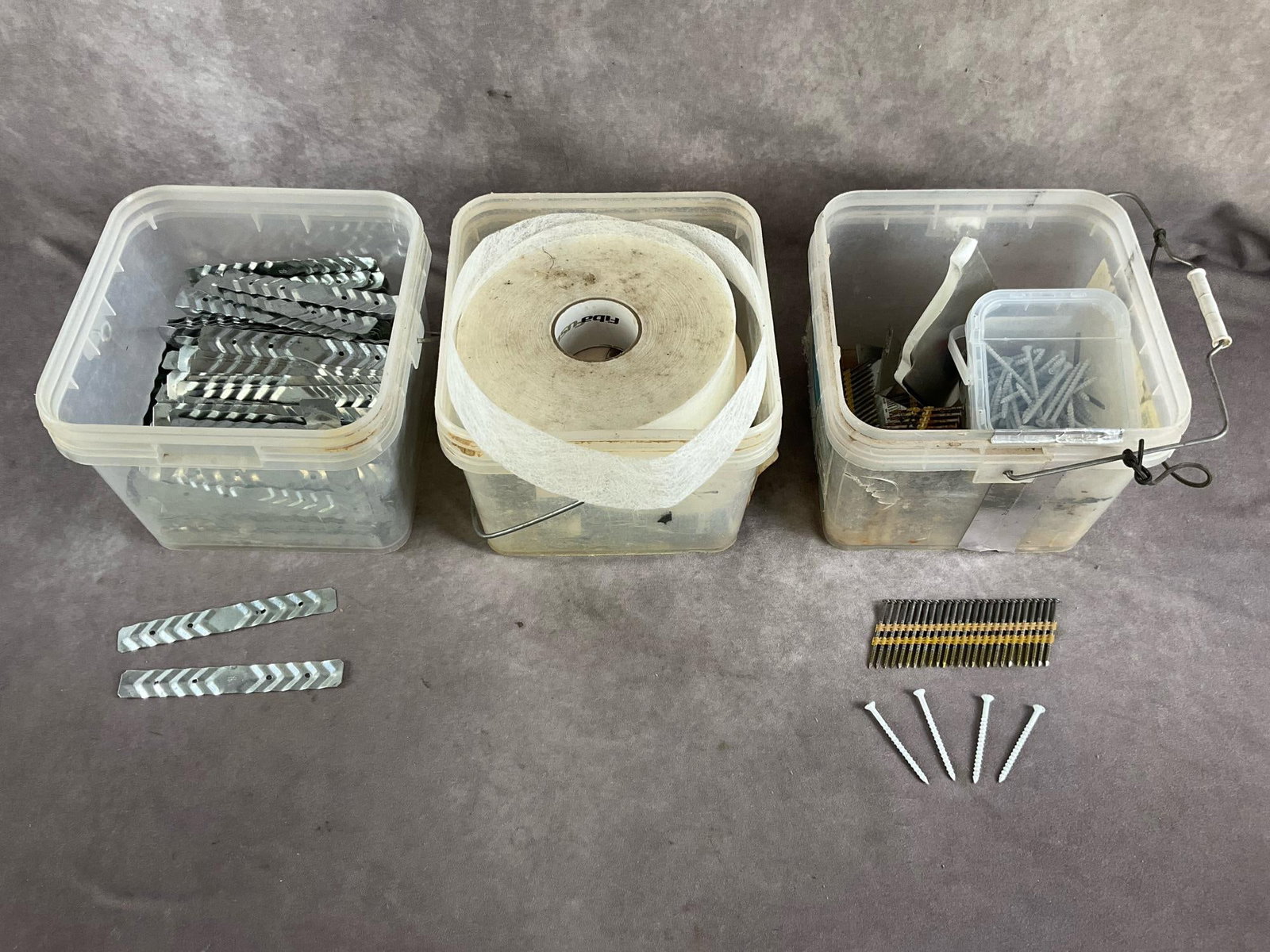 Assorted Construction Items: BT 22 gauge brick ties, paperless drywall tape and nails and screws. Unused and in good condition. Box measures 9 1/2 inches square X 8 inches high.