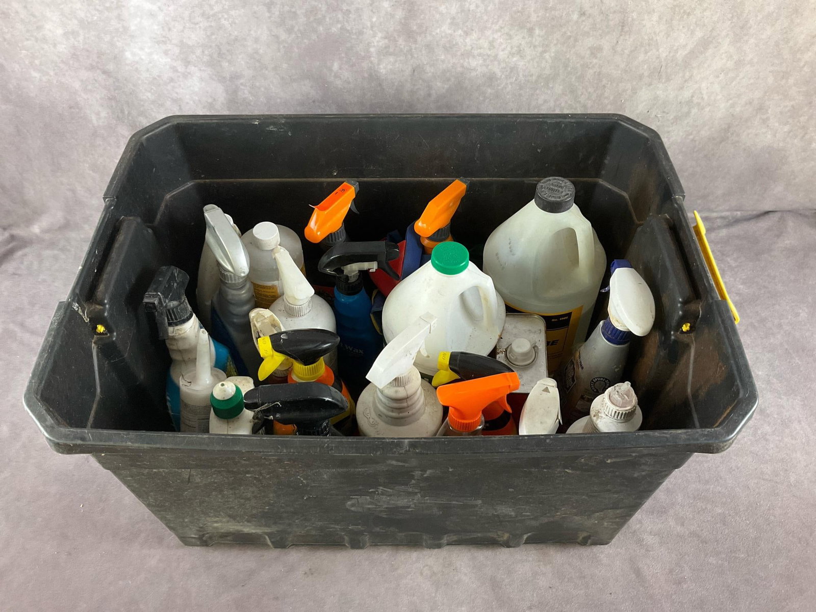Tote of Cleaning Supplies: Assorted industrial cleaners including, wood cleaner, paint remover, floor finish, tire shine, car wax, and others. Used. Tote measures 25 inches long X 18 inches wide X 13 inches high.