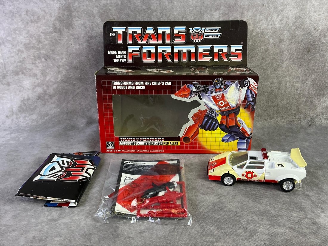 Red Alert Transformer: 1985 Transformers, Red Alert Autobot Security Director made by Hasbro, Japan. In fair condition with original box, has been opened, broken gun piece, creasing and bowing to box. Measures 8.5 inches