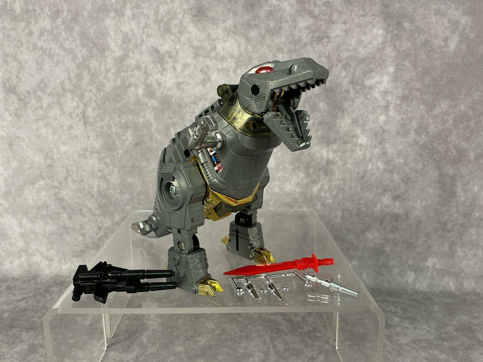 Grimlock Transformer: 1985 Grimlock Dinobot Transformer generation one with one gun, a red sword, and all three missles. Missing one black gun. Good condition, some wear to tail. Measures 3 inches wide x 6 x 4.75 inches