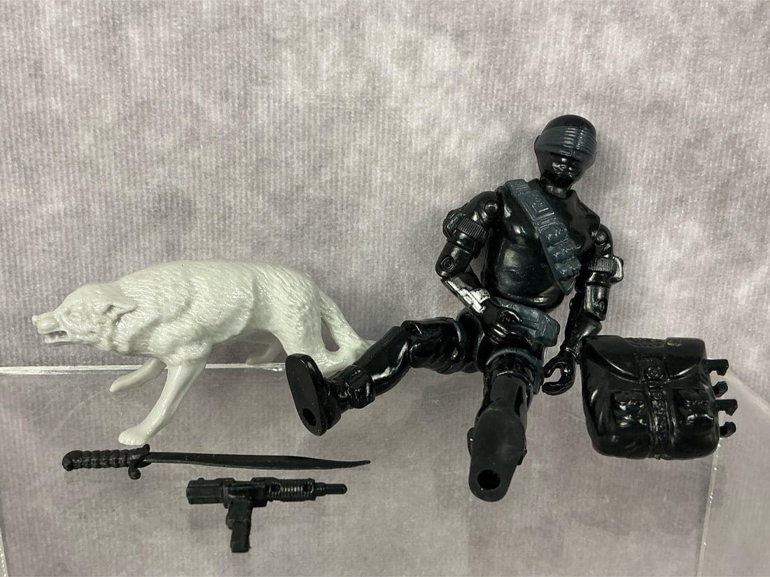 Snake Eyes G.I. Joe: 1985 Snake Eyes G.I. Joe made by Hasbro in Hong Kong. Complete with pet wolf , backpack, sword, and gun. Tight joints, loose torso, and small paint loss to silver band on arm. Figure measures 1.5
