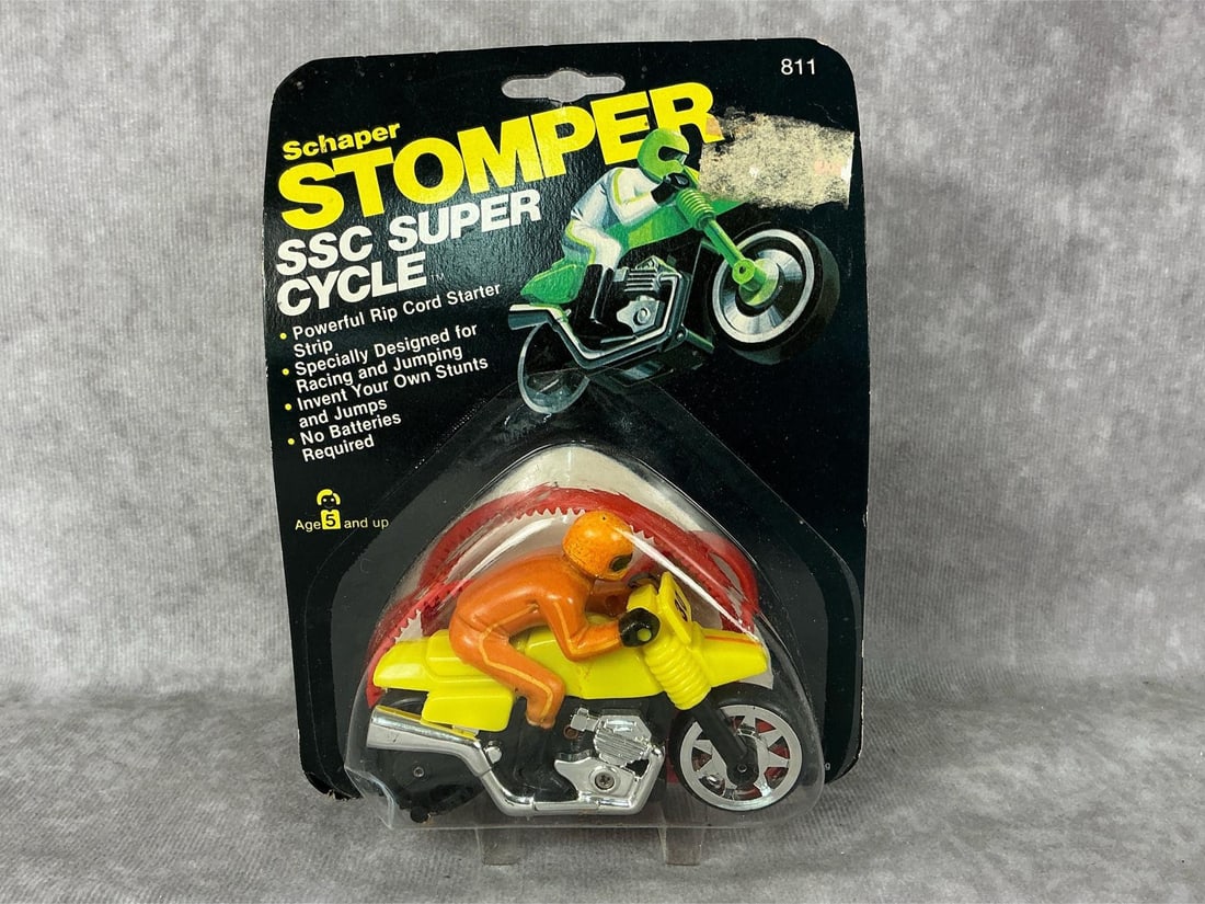 Stomper Super Cycle: 1981 Schafer Stomper SSC Super Cycle in original packaging, made in Hong Kong. Packaging has heavy wear. Measures 4.75 x 6.25 inches tall.