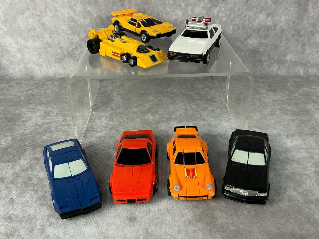 GoBots: Seven 1980s GoBots, five marked Bandai made in Japan, one marked Hasbro Japan, other one unmarked. Includes Lamborghini, Police Car, Porsche, Mercedes, Corvette, Drag Car, and a Nissan 280Z. Light wea