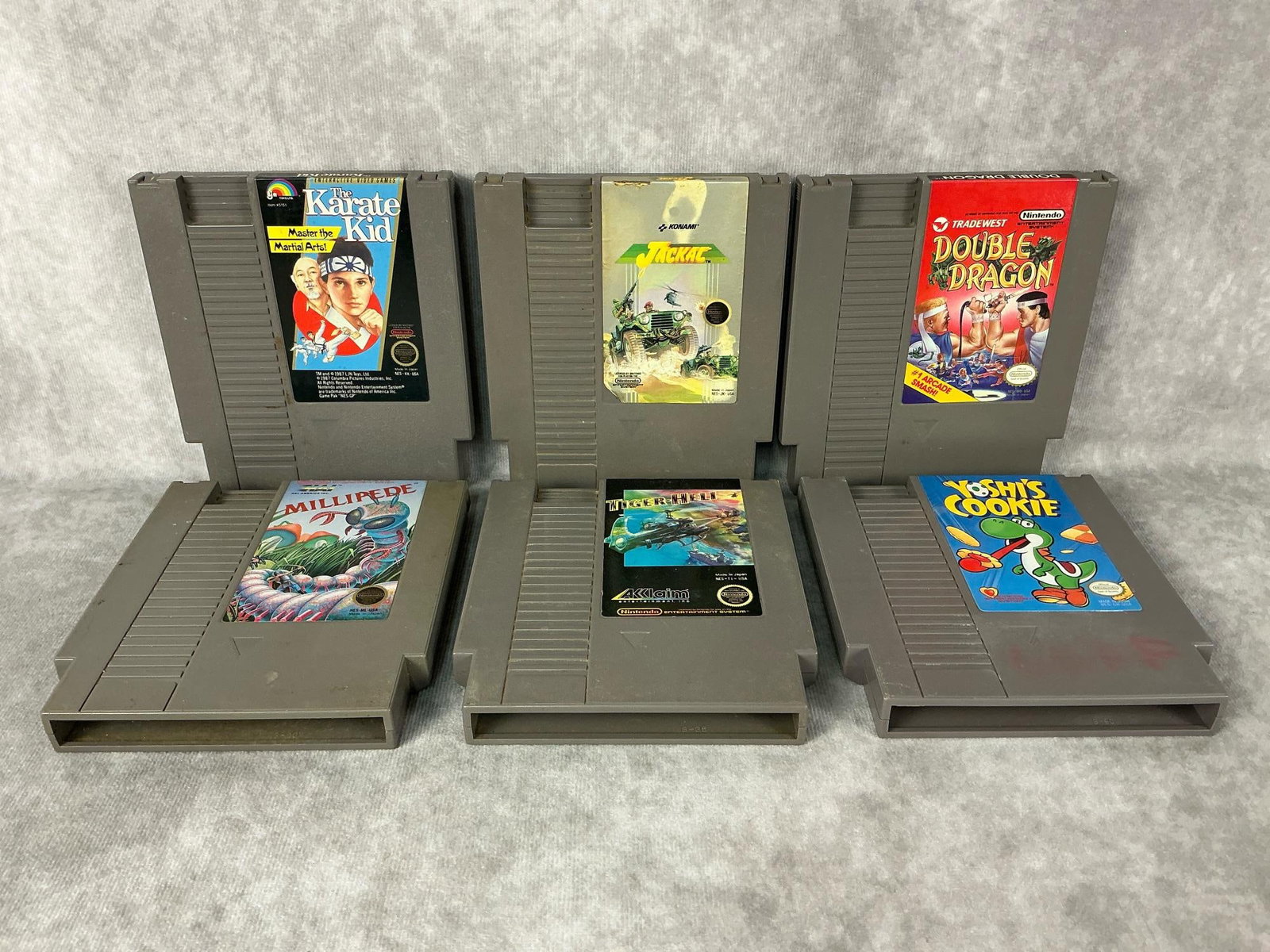 Nintendo Games: Six vintage original Nintendo NES games, includes Jackal, Tiger-Heli, Karate Kid, Double Dragon, Yoshi’s Cookie, and Millipede. All are untested and in fair condition, yellowing and wear to outside.