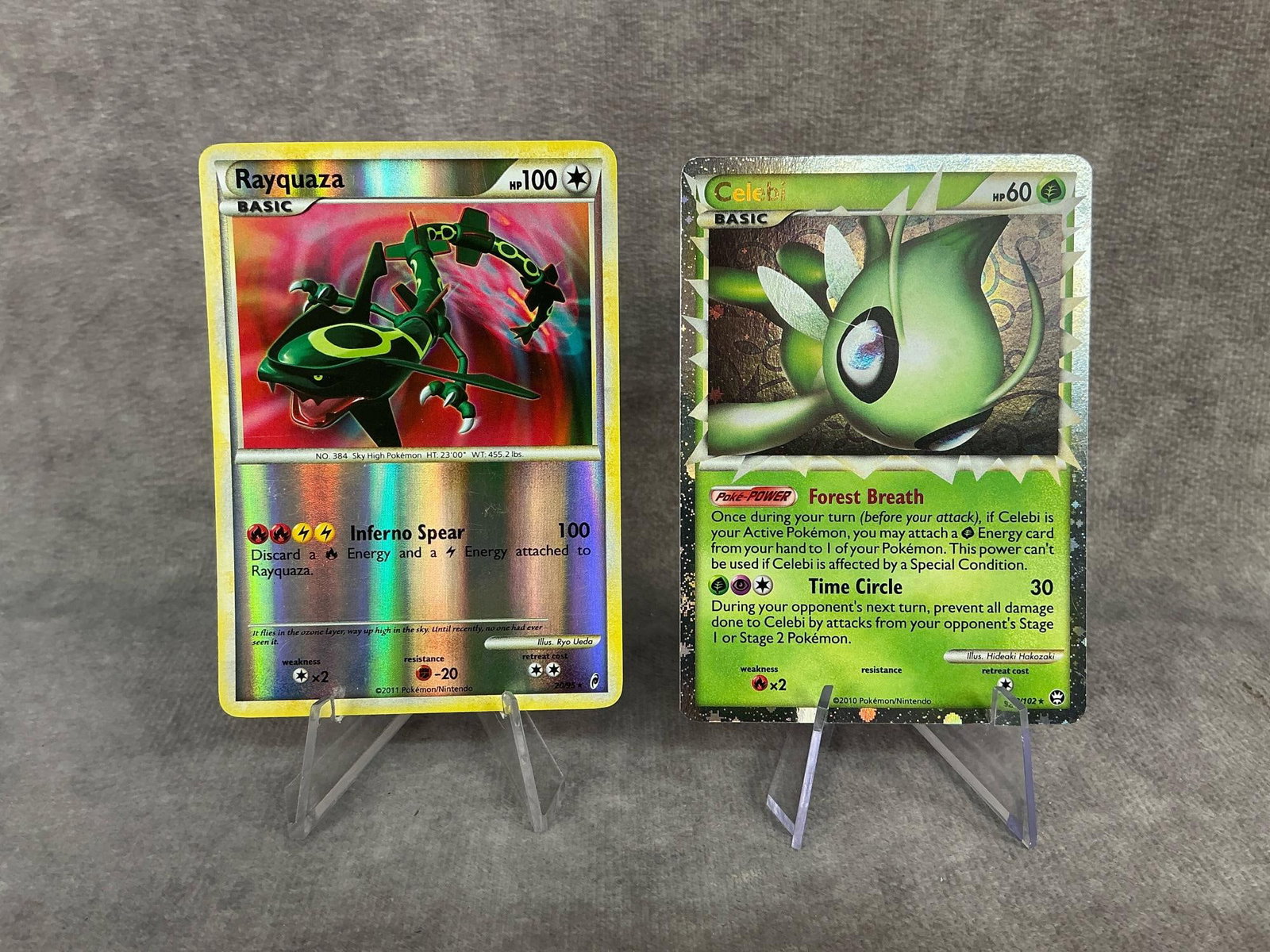 Holographic Pokemon Cards: 2011 Rayquaza basic reverse holographic card 20/95, and a 2010 Celebi basic holographic card 92/102. Bowing on both cards, otherwise good condition. Each one measures 2.5 inches wide x 3.5 inches