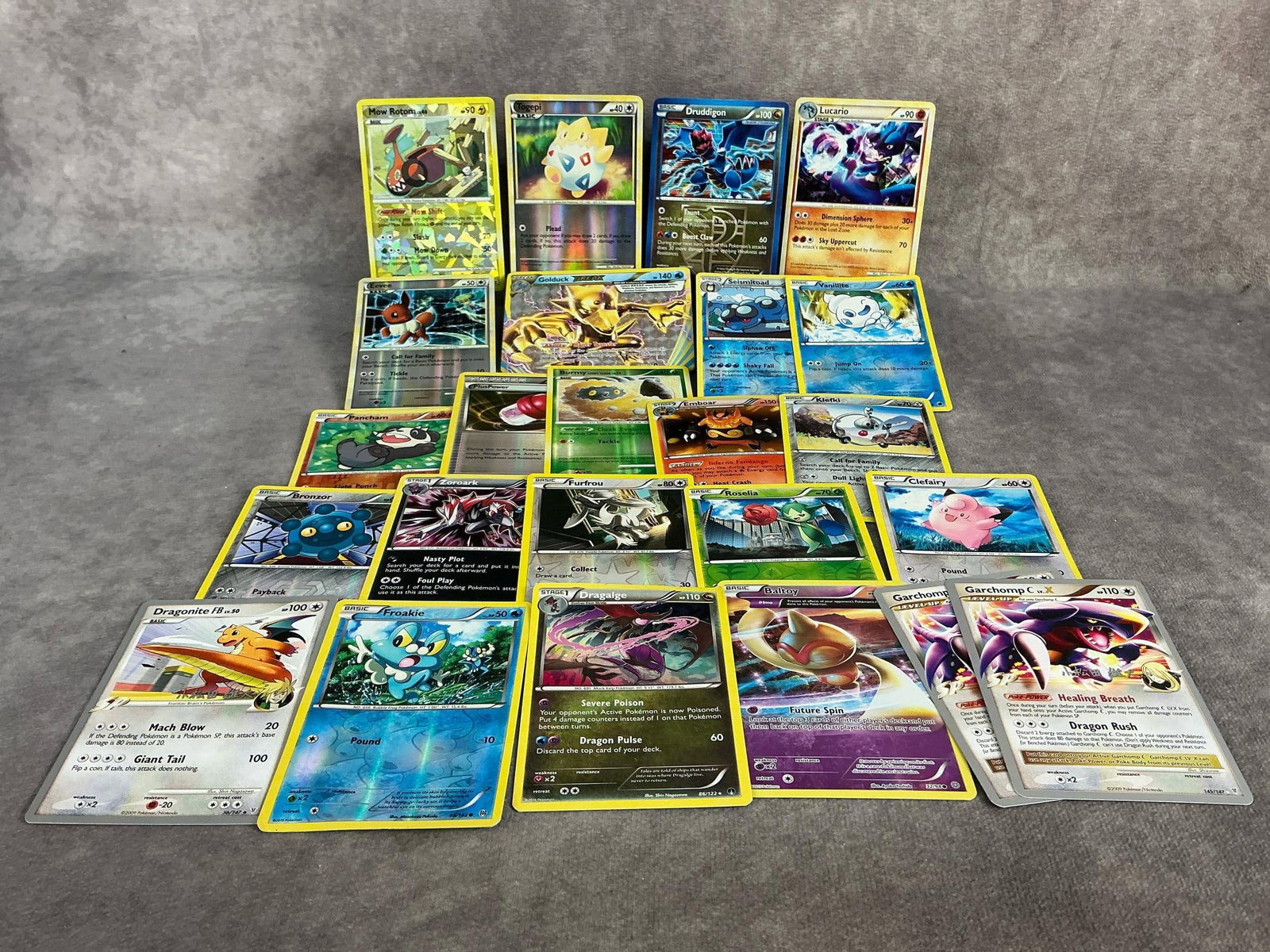 Holographic Pokemon Cards: Twenty four Pokemon cards from 2009-2016, includes holographic, reverse holographic, and non-holographic cards. Top cards are Druddigon, Togepi, Mow Rotom, Evee, and Golduck. Garchomp and Dragonite