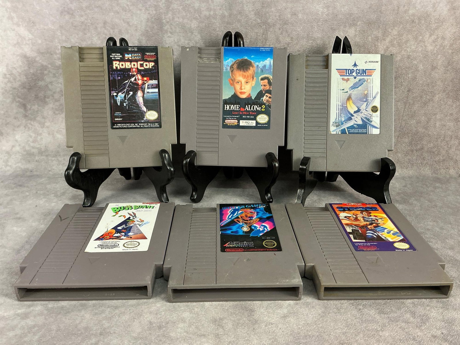Nintendo Games: Six vintage original Nintendo NES games. Includes Robo Cop, Home Alone 2, Top Gun, Bugs Bunny, Winter Games, and Strider. All are untested and have general wear annd some yellowing. Each one measures