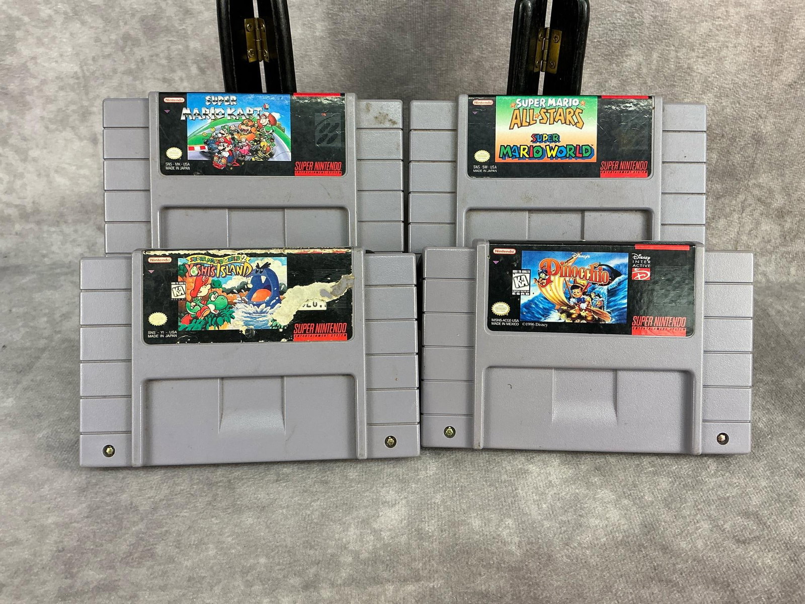 Super Nintendo Games: Four vintage original Super Nintendo games. Includes Mario Kart, Super Mario All Stars, Yoshi’s Island, and Pinocchio. All are untested, some have yellowing. Each one measures 5.25 inches wide x