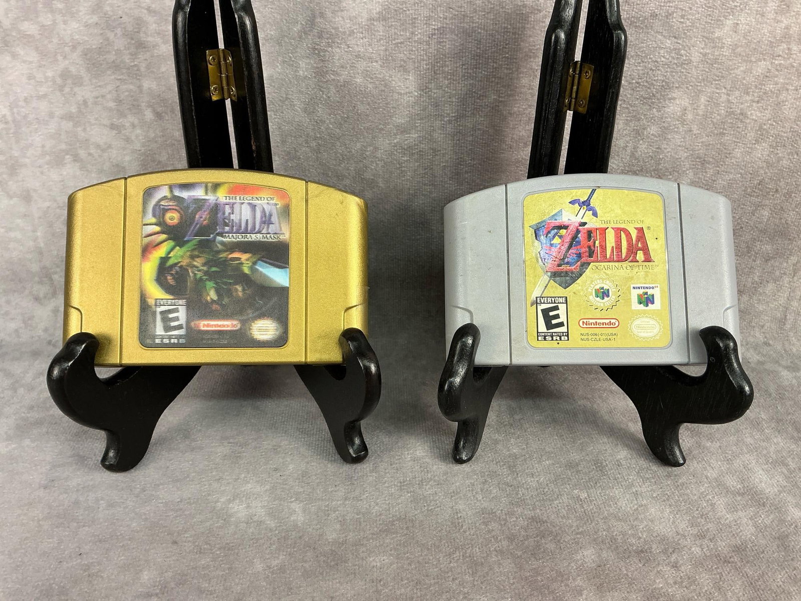 Nintendo 64 Games: Two vintage original Nintendo 64 games, Zelda Ocarina of Time and Zelda Majora’s Mask. The gold one has a lenticular label on the front. Both games are untested and have wear, broken piece on