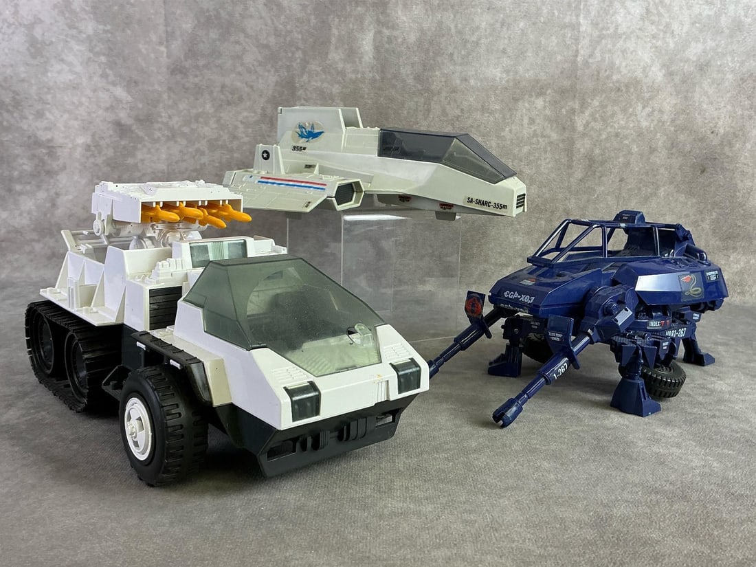 GI Joe Vehicles: Three G.I. Joe vehicles including 1984 GI Joe S.H.A.R.C vehicle, 1984 GI Joe Cobra Assualt System Pod vehicle, and 1985 GI Joe Snow Cat vehicle. All missing parts and in fair used condition. Snow Cat 