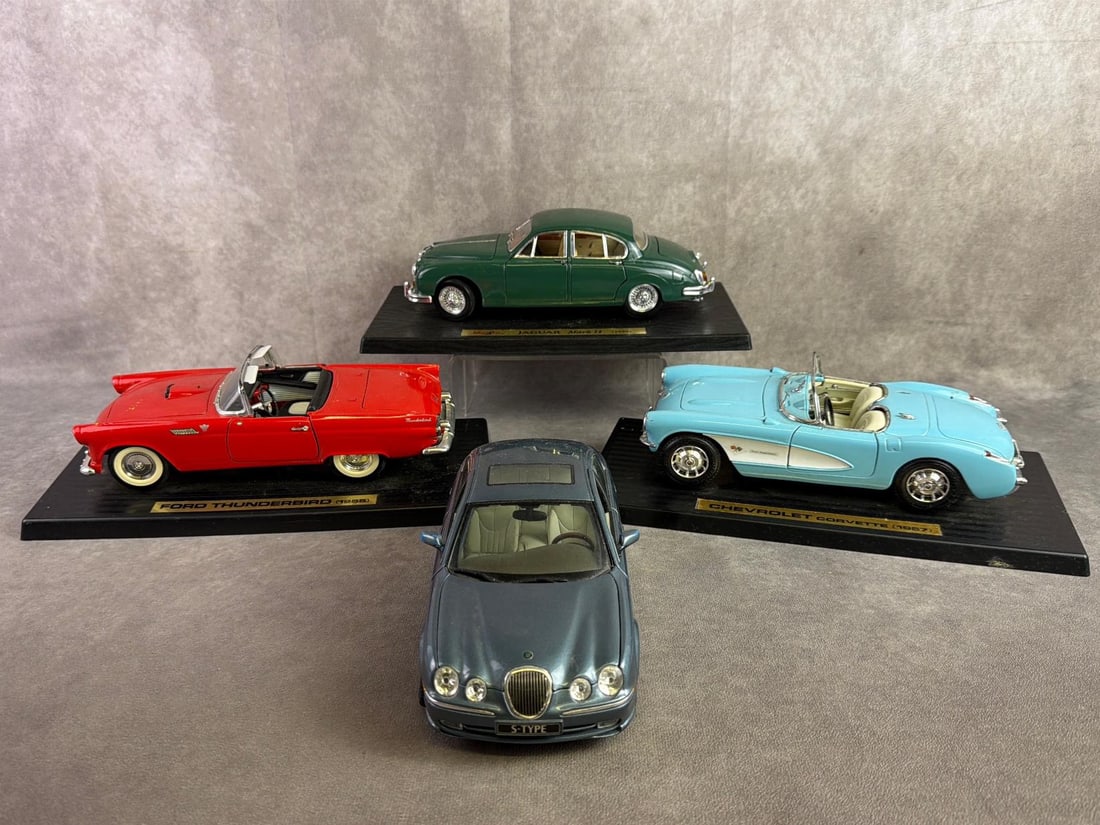 Maisto Model Cars: Four Maisto model cars including 1959 Jaguar, 1955 Thunderbird, 1957 Corvette, and Jaguar S Type. All in good condition. Platform measures 12 inches wide x 5.5 inches tall.