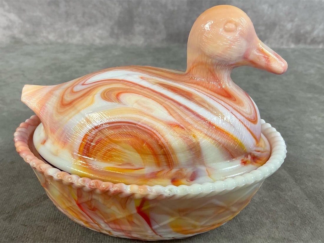Swirled Glass Duck on Nest: Vintage Westmoreland duck on nest. Swirled orange, yellow, and white glass with stamp on bottom. In good condition. Measures 5.5 inches wide x 4.25 x 4.25 inches tall.