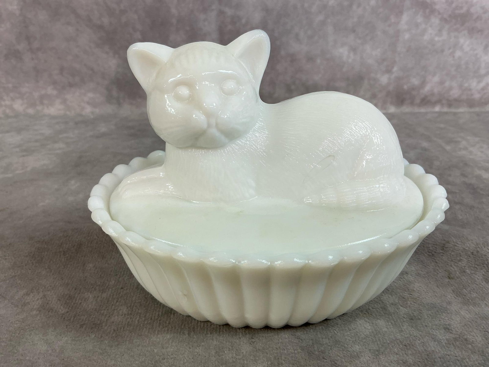 Westmoreland Cat in a Basket: Mid 1900's Westmoreland cat on a basket dish. White milk glass cat on ribbed basket. In good condition. Measures 5.5 inches long x 4 x 4 inches tall.