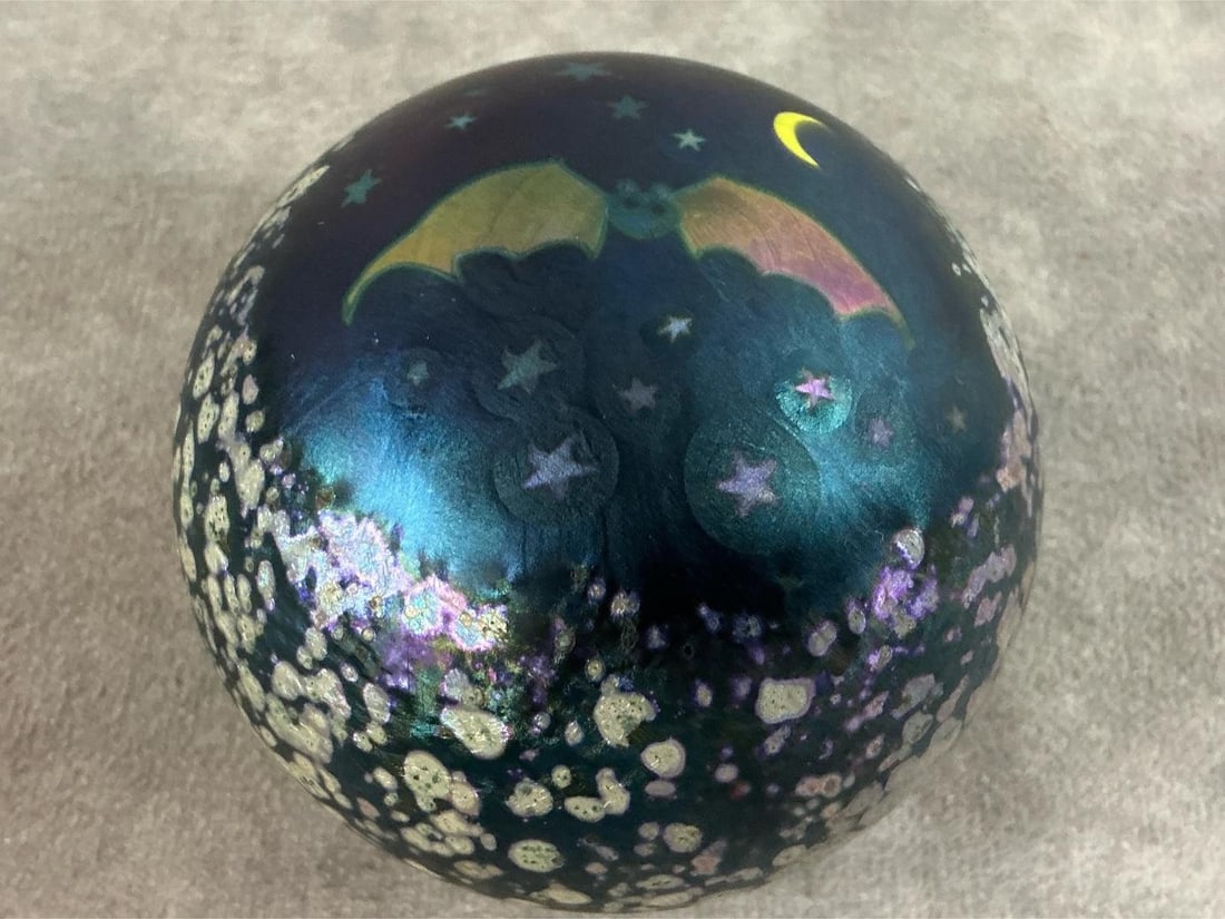 Bat in Night Sky Paperweight: 1976 iridescent "night sky" paperweight by Lundberg Studios. Marked 57/300. In good condition. Measures 3 inches in diameter x 2.5 inches tall.