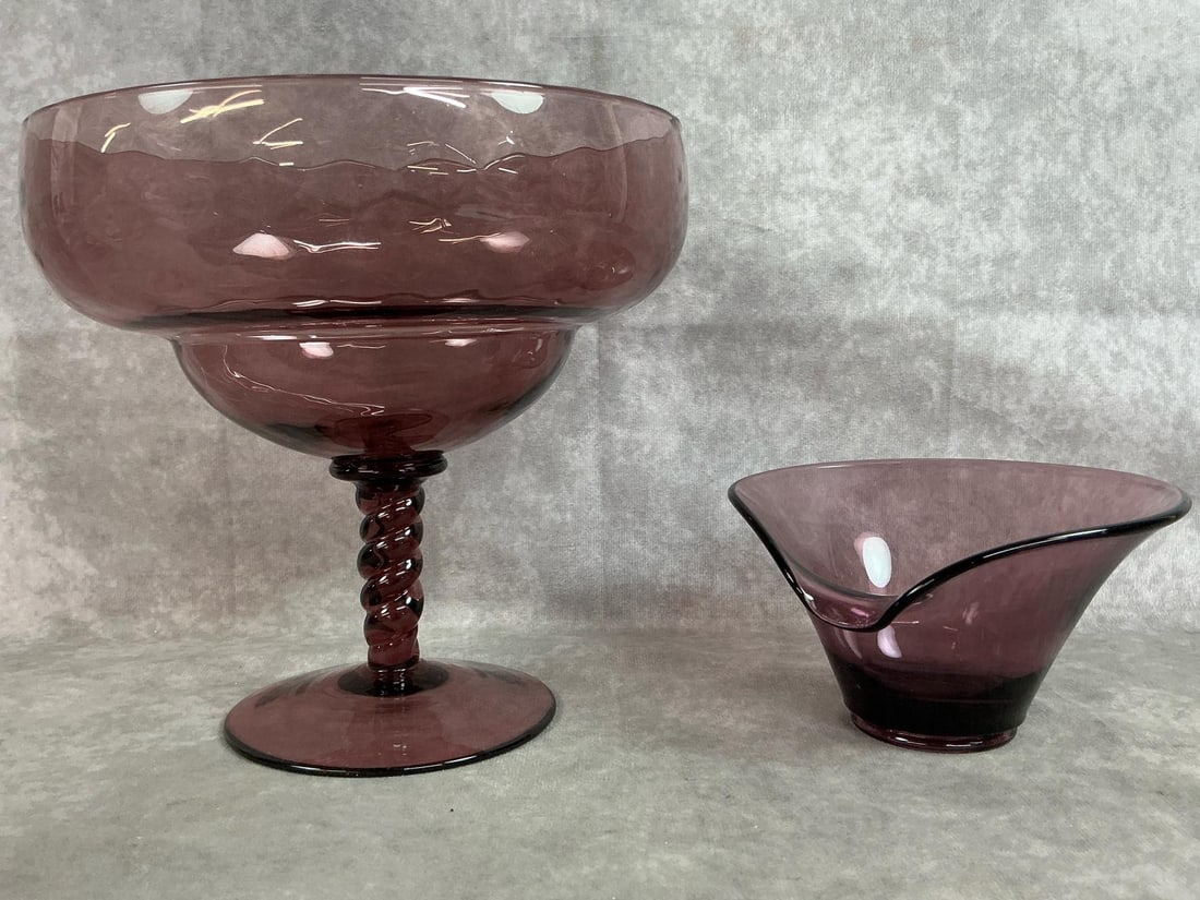 Amethyst Glass: Two mid 1900's Amethyst glass. Large Empoli glass compote optic glass design with twisted stem. Viking Calla Lily glass bowl. Both in good condition. Empoli measures 8.5 inches at rim x 8.5 inches