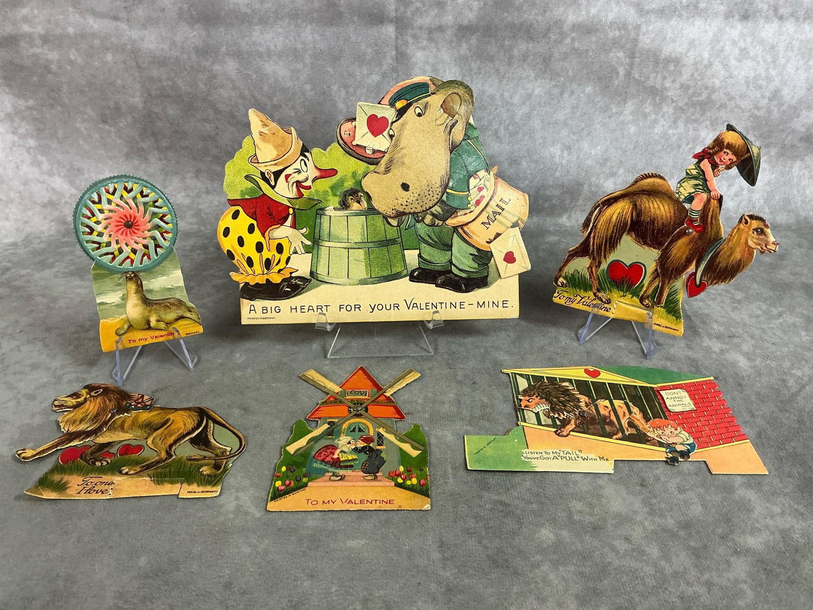 Vintage German Valentines: Six early 1900's German valentines. Hinged with moving parts. Marked on back. Lion is missing a figure on its back, otherwise in good condition. Hippo and clown card measures 6.5 inches in diameter x