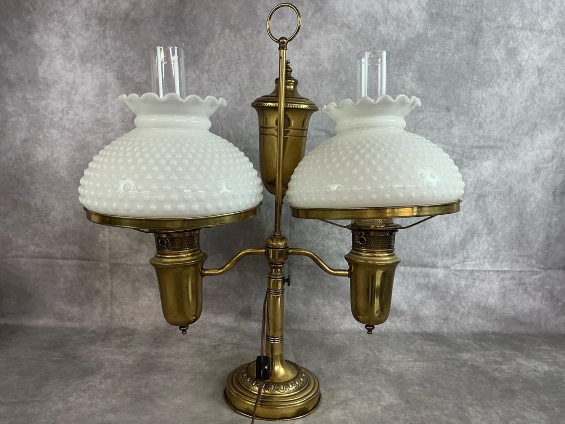 Double Arm Brass Lamp: Early 1900's Victorian style double lamp. Polished brass stand with white milk glass hobnail shades. Some tarnish present, otherwise in good working condition. Measures 22 inches wide x 12 x 24