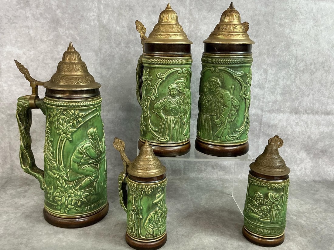 German Beer Steins: Five early 1900's German beer steins. Green ceramic steins with pewter lidded top. Pub scene on each stein. In good condition. Measures 4 inches in diameter x 11 inches tall.