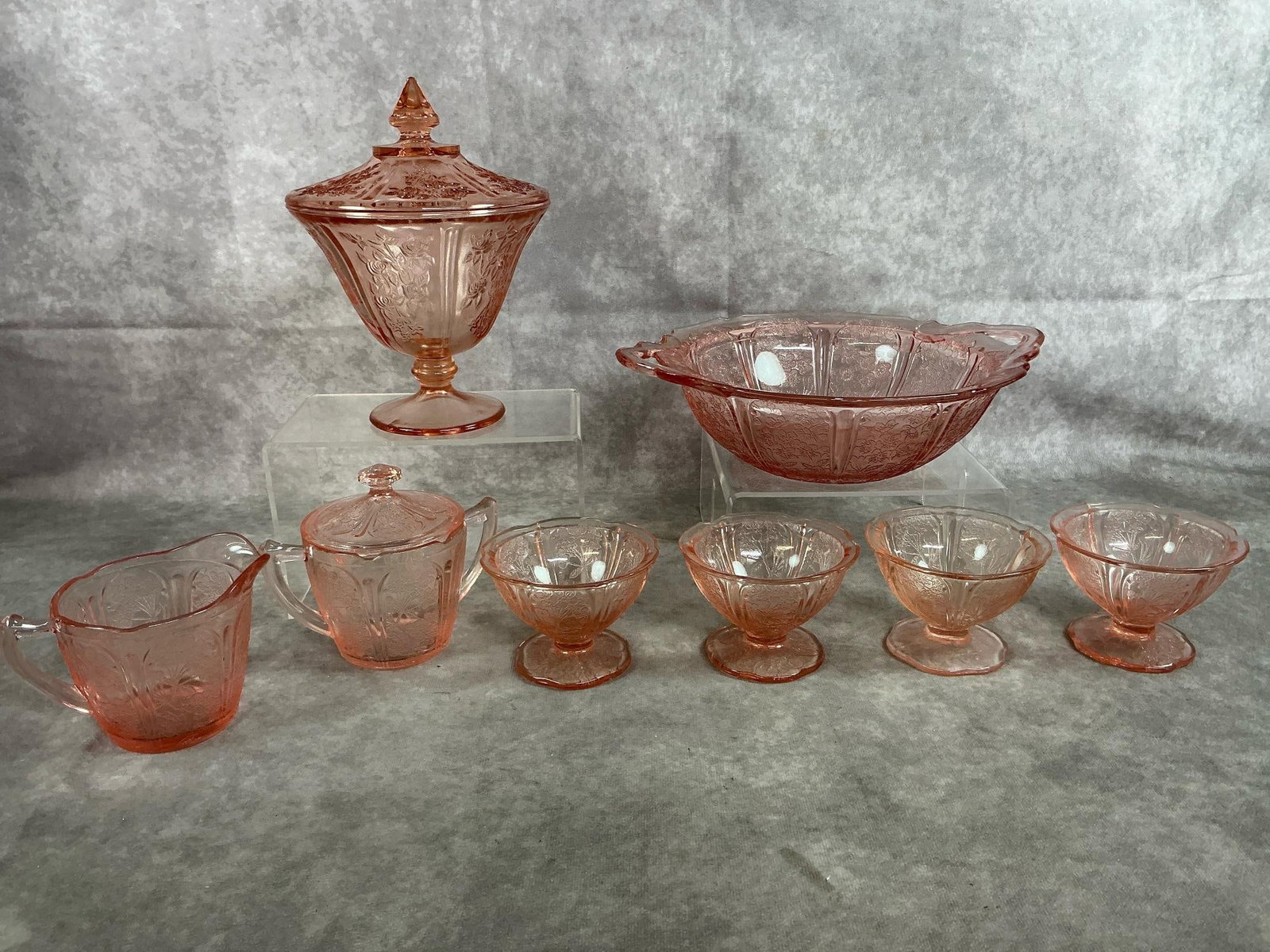 Pink Depression Glass: Eight early 1900's pink Depression glass. Floral Federal Glass "Sharon" candy jar with lid. Jeannette Glass with Cherry Blossom pattern includes serving dish, sugar and creamer, and four sherbet