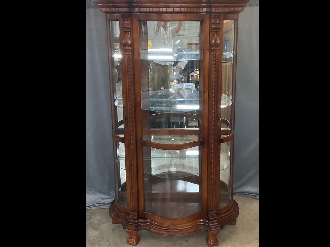 Curio Cabinet: Contemporary carved curio cabinet with back mirror, lighting and four adjustable glass shelves. Good condition. Lighting not tested. Measures 44 inches wide x 20 x 81.5 inches tall.