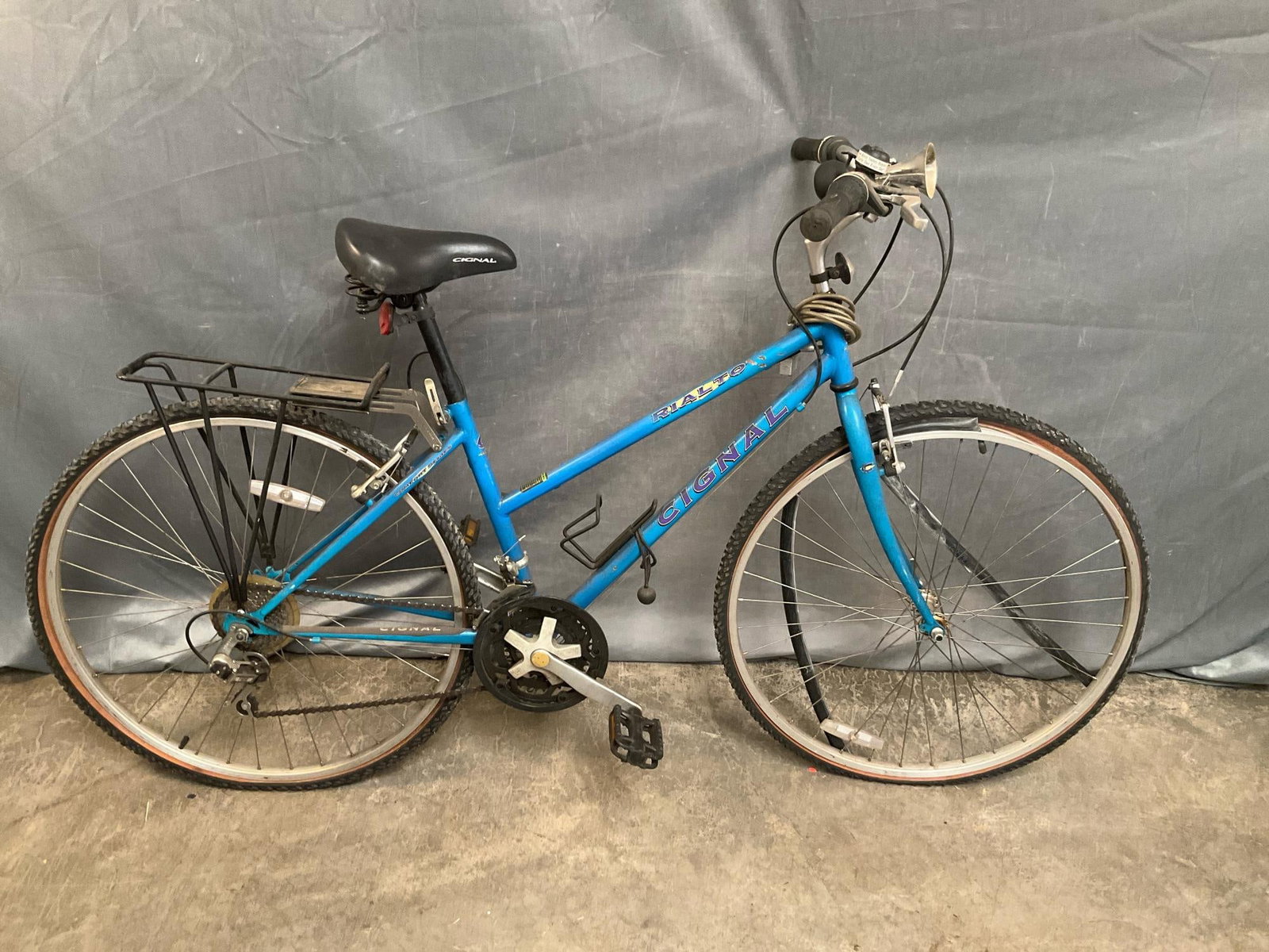 Cignal Rialto Bicycle: 1990's Cignal Rialto Women's bicycle with Shimano derailleurs, rack, horn and lock without key. Tube not on tire, used condition, not tested. Measures 66 inches wide x 14 x 43 inches tall.