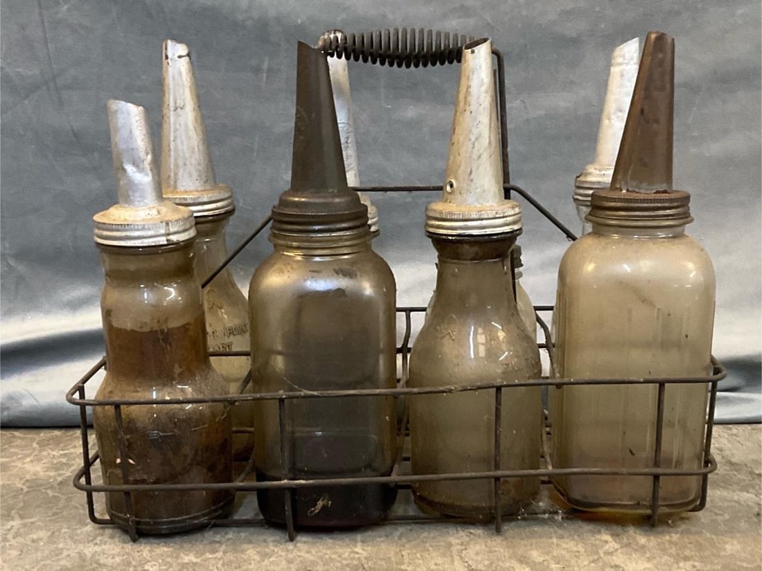 Glass Motor Oil Bottles: Eight 1920's antique glass motor oil bottles with wire carrier. Used condition, otherwise good condition. Carrier measures 18.5 inches wide x 10 x 14 inches tall.